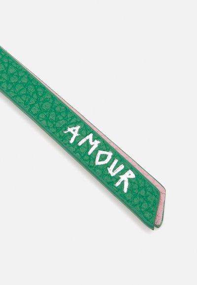Zelený kožený řemínek s texturovaným povrchem, s růžovým okrajem a slovy "AMOUR" bílým písmem.