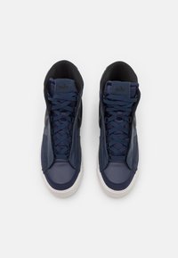 Höga sneakers i marinblå syntetiskt material, med kontrasterande svarta detaljer, snörningsdesign och vit gummisul. Har logotyp på tungan.