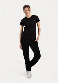 Czarny bawełniany t-shirt oraz dopasowane spodnie dresowe. Koszulka ma okrągły dekolt i małe logo. Spodnie są luźne, z bocznymi kieszeniami.