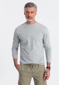 Grå långärmad t-shirt med rund halsringning och en mjuk yta, kombinerad med khaki cargoshorts som har sidofickor och dragsko i midjan.