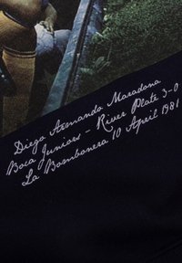 Zwarte stof met een textuurontwerp en witte handgeschreven tekst, met details over de wedstrijd en datum van Diego Maradona, wat wijst op een sportthema.