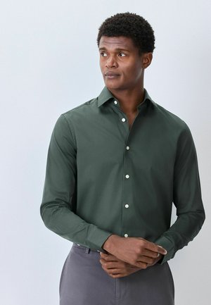 Dark green button-up shirt with a structured collar, long sleeves, and subtle texture. Features white buttons and a tailored fit.