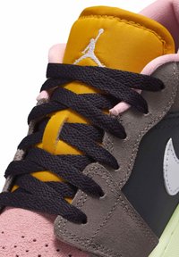 Višebojne sportske tenisice s rozom osnovom od nubuka, sivim kožnim detaljima, žutom najlonskom jezičkom i tamnim vezicama s bijelim logotipom.