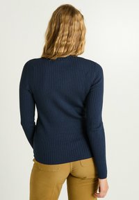 Pull en maille côtelée de couleur marine, à manches longues et col rond, présentant une silhouette ajustée et un tissu texturé.