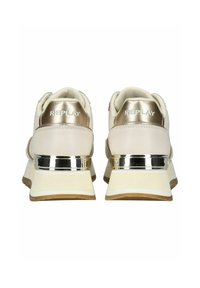 Baskets basses beiges avec des accents métalliques dorés, dotées d'un col rembourré, de côtés texturés, d'une semelle en caoutchouc plate et d'un logo en relief sur le talon.