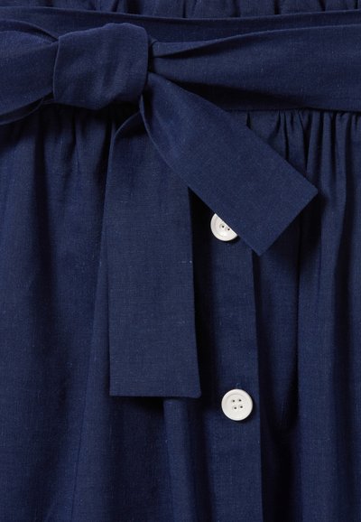 Robe en lin bleu marine avec une ceinture à nouer à l'avant, un design plissé et des boutons en plastique blanc sur le devant pour fermer.