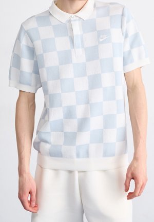 Lysblå og hvidt ternet polo skjorte med krave, der har et Nike-logo i hvid. Stoffet har en tekstureret finish og ribbet kant.