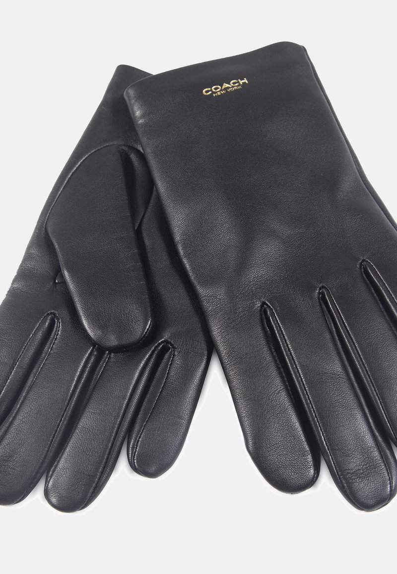 Gants en cuir noir au toucher lisse, avec un design minimaliste et un logo de marque subtil en or au niveau du poignet.