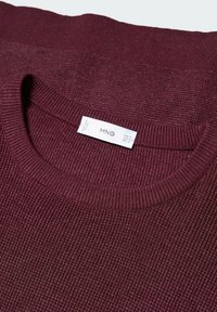Burgundowa dzianinowa sweter z ryżowym wzorem, z okrągłym dekoltem i metką wskazującą rozmiary EU M, US M i MX M.
