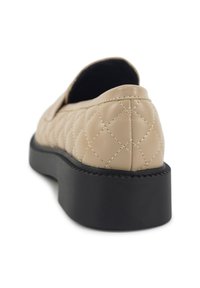 Beige, gewatteerde instap schoen met een ronde neus, dikke zwarte zool en zichtbare stikdetails langs de naden. Zacht, gestructureerd leren materiaal.