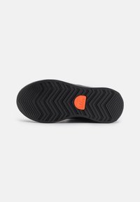 Sorte svart gummisko med zigzag-mønster og oransje logo. Har teksturert overflate og forsterkede kanter for holdbarhet.