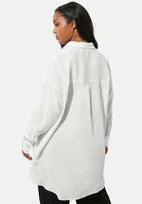 Witte blouse met lange mouwen van lichtgewicht stof, heeft een relaxte fit, puntige kraag, knoopmanchetten en een gebogen onderrand.