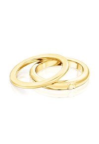 Dwa połączone ze sobą złote pierścienie o gładkim, polerowanym wykończeniu. Jeden z pierścieni ma mały ozdobny emblem, oba mają kształt okrągły.