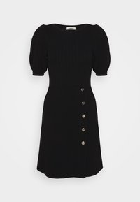 Robe noire longueur genou avec manches courtes bouffantes, corsage ajusté côtelé et boutons décoratifs argentés sur un côté de la jupe.