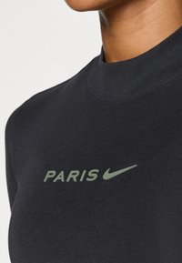 Mustaga pikkade varrukatega särk kõrge kaelusega, millel on tagasihoidlikult kujundatud roheline "PARIS" logo ja Nike'i sikk-sakk. Pehme ja sile tekstuur.