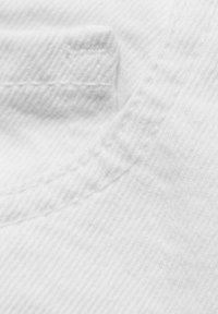 Tissu blanc à armure texturée avec un léger éclat, présentant un col arrondi et des détails de couture visibles.