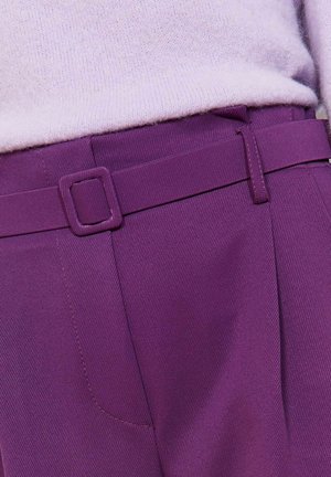 Lillasest värvist püksid tekstuurse kangaga, millel on ruudukujuline vöölõng, kitsas lõige ja täpsed õmblused tasku lähedal.