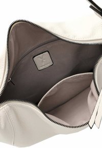Interno di una borsa di pelle bianca con foderatura in morbido tessuto, tasca con cerniera e etichetta del marchio rettangolare strutturata. I bordi sono lisci con cuciture a contrasto.