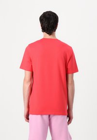 Röd bomulls-T-shirt med klassisk rund halsringning och korta ärmar, med en mjuk textur och avslappnad passform. Inga grafiska detaljer synliga.