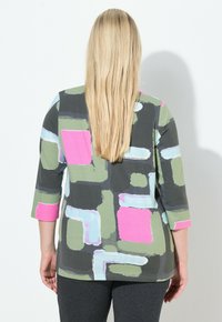 Barevný top s tmavě šedým základem a živými zelenými, růžovými a světle modrými abstraktními vzory a rukávy tříčtvrteční délky.