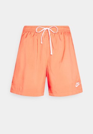 Koraaloranje Nike zwembroek met elastische tailleband, witte treksnor en wit Nike-logo op het linkeronderbeen.