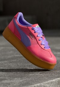 Pink and purple platform sneaker with smooth leather upper, textured rubber sole, and contrasting laces. Features branded logo on the side.