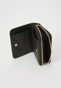Portefeuille en cuir noir avec fermeture éclair, quincaillerie dorée, plusieurs emplacements pour cartes et deux compartiments pour billets ou pièces.