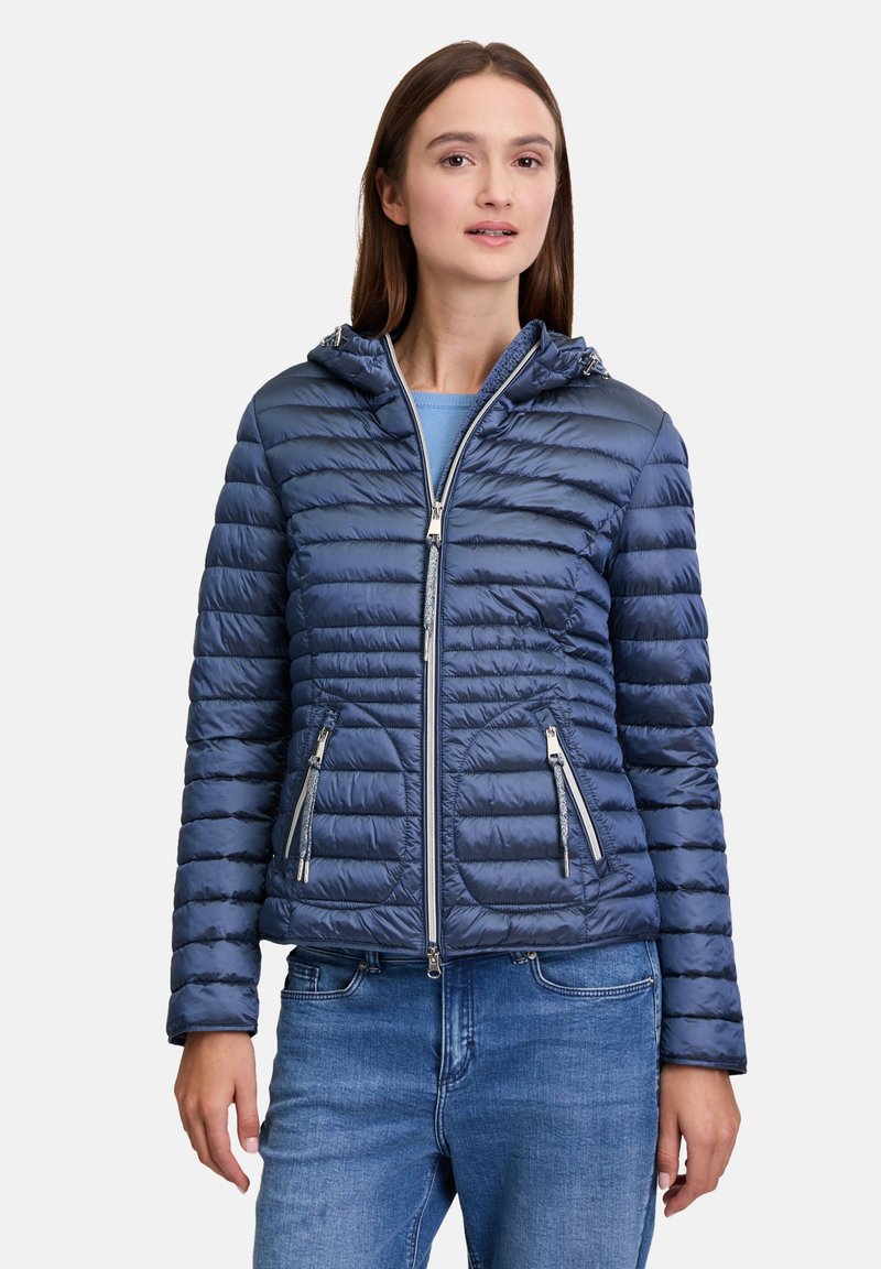 Marineblauwe pufferjack met horizontaal gestikte uitstraling, met ritszakken en capuchon. Het gladde, glanzende stof vergroot de warmte en het comfort.