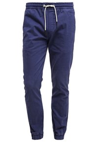 Marineblauwe joggers met elastische tailleband, witte trekkoord en elastische boorden, weergegeven tegen een witte achtergrond.