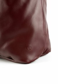 Burgundy leather bag with a soft texture, featuring a subtle embossed "L37" on the base, rounded shape, and minimalistic design.