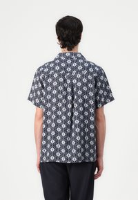 Camicia a maniche corte realizzata in tessuto a righe blu e bianco con un design floreale, colletto button-down e vestibilità comoda.