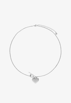Collier à chaîne fine en argent avec pendentif en forme de cœur et fermoir à bascule sur fond blanc.