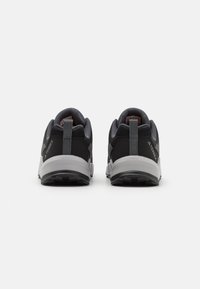 Chaussures de sport noires et grises avec tige en maille, cols rembourrés et semelles en caoutchouc. Présente des accents gris contrastants et des languettes à l'arrière.