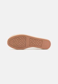 Suola di scarpa in gomma di colore beige, con un motivo floreale e geometrico per una migliore aderenza, caratterizzata da una texture liscia e una forma arrotondata.