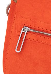 Bolso de ante naranja con un bolsillo con cremallera y herrajes plateados, que muestra una textura suave y costuras precisas.