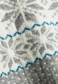 Weicher gestrickter Stoff mit grau-weißen Schneeflockenmuster und blauen Zickzacklinien in einem winterlich gestalteten Design.