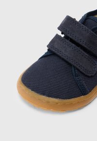 Pehme sinine laste jalanõu tekstureeritud kangast pealsega, kahe takjapaelaga ja heledat pruuni värvi kummist tallaga.