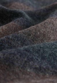 La tela de lana texturizada presenta una mezcla de tonos azul oscuro, gris y marrón, con variaciones sutiles en la profundidad y una superficie suave y pelusa.