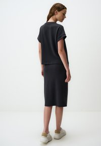 Ciemnoszary, krótko rękawowy top połączony z dopasowaną, sięgającą kolan spódnicą. Gładka tekstura, prosty design, noszony z białymi trampkami.