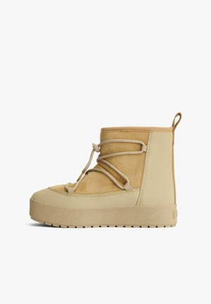 Beige mockaskinn- och gummistövlett med en strukturerad sula, snörning fram och en ögla vid hälen för enkel påtagning.