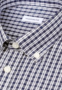 Chemise à carreaux bleu marine et blanc avec col à boutons et étiquette de la marque Seidensticker à l'intérieur du col.