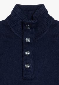 Polo in maglina blu navy con colletto alto, dotato di quattro bottoni argentati sul davanti e texture a costine sul colletto e sul bottone.