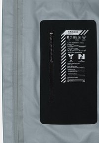 Grauer Stoff mit einem schwarzen Panel, das weißen Text und Symbole enthält. Enthält eine Reißverschlusstasche und Notfallinformationen in einer klaren Anordnung.