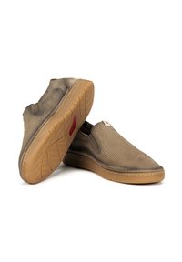 Chaussures à enfiler en maille marron avec une tige perforée et une semelle en caoutchouc gomme. Équipées de panneaux latéraux élastiques pour un enfilage facile.