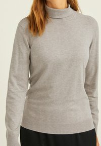 Szary sweter w stylu golfowym, wykonany z miękkiego materiału, z długimi rękawami oraz żebrowanym wykończeniem przy kołnierzu i hemie, o gładkiej fakturze.