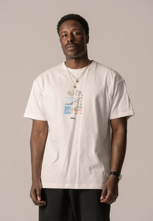 T-shirt en coton blanc à manches courtes avec un graphique coloré de fenêtre au centre, intégrant des éléments floraux et des paysages.