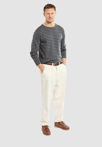 Camicia a maniche lunghe a righe blu navy e grigia, pantaloni crema, cintura marrone e scarpe marroni con lacci; vestibilità rilassata e tessuto testurizzato.