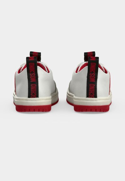 Baskets blanches et rouges vues de dos avec des languettes noires au talon portant un texte rouge "MOSCHINO".