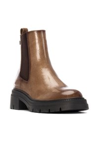 Botín de cuero marrón con un acabado brillante, paneles laterales elásticos y suela gruesa de goma negra con un patrón de banda de rodadura texturizado.