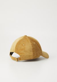 Brown corduroy cap featuring a curved visor, textured fabric, adjustable back strap, and six-panel design with ventilation holes.